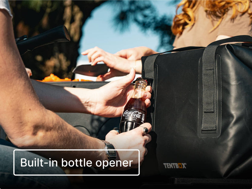 Person opening a Coca-Cola bottle using the built-in bottle opener on the side of the TentBox CoolBag.