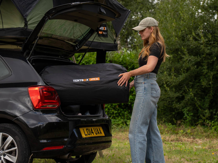 Woman loading packed TentBox Lite XL Mattress Topper into vehicle boot – compact and transportable