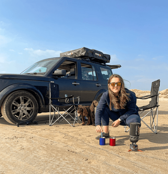 Woman on beach with TentBox roof tent in background